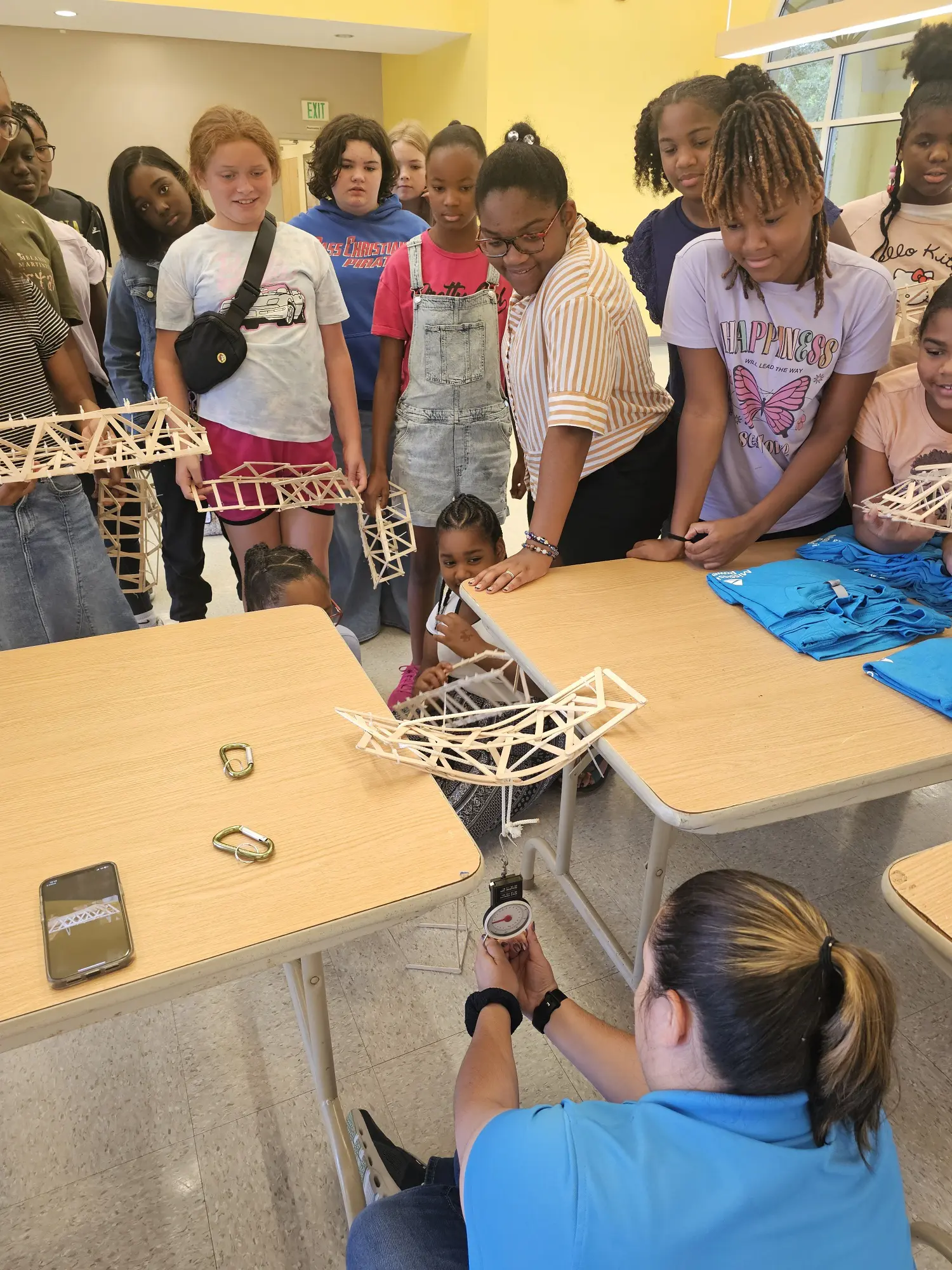 Diverse young girls enthusiastically participating in a STEM workshop, building educational projects with craft supplies at a bright, collaborative learning space.